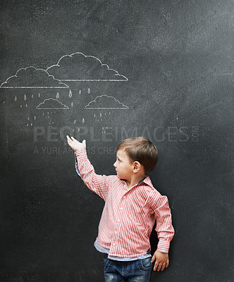 Buy stock photo A young boy showing drawings of rain clouds on a blackboard
