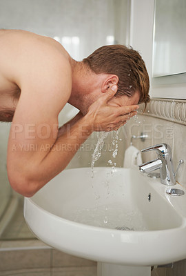 Buy stock photo A handsome man washing his face in a bathroom