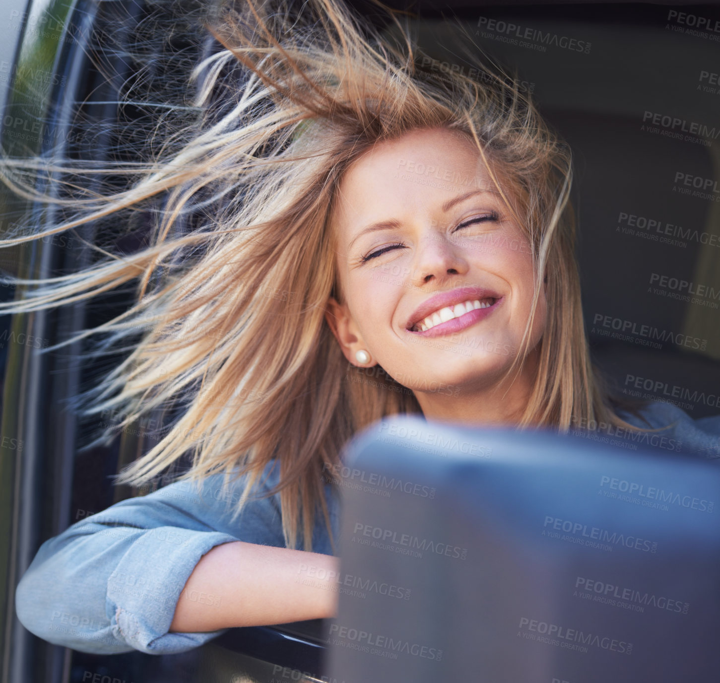 Buy stock photo A young woman feeling the breeze in her hair through an open car window