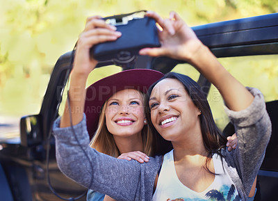 Buy stock photo Shot of a two girlfriends taking self-portraits while on a roadtrip