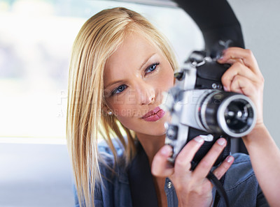 Buy stock photo Shot of an attractive young woman sitting in a car taking pictures with an old camera