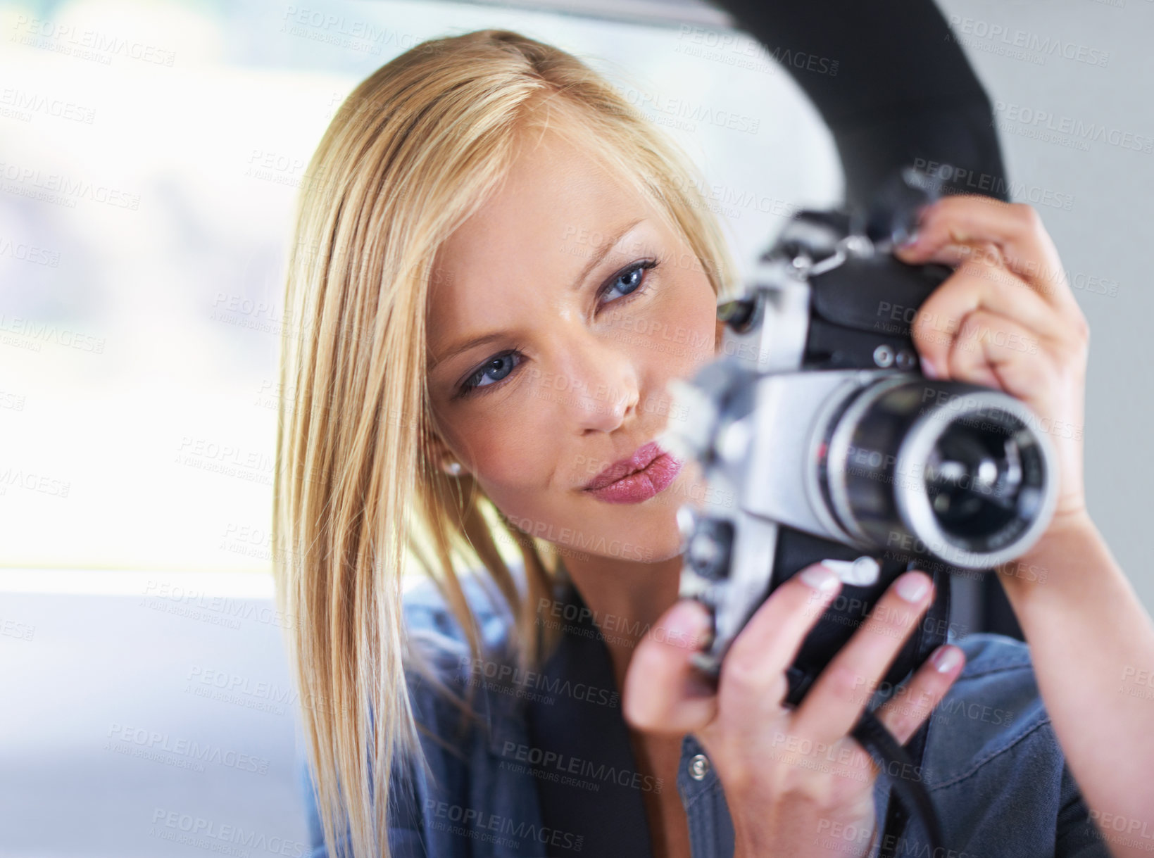 Buy stock photo Shot of an attractive young woman sitting in a car taking pictures with an old camera