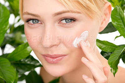 Buy stock photo Portrait, skincare and woman with cream by leaves isolated on a studio background for health or hydration. Face, cosmetics and natural model with lotion for organic facial moisturizer or dermatology