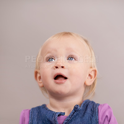 Buy stock photo Thinking, happy baby and cute in studio with expression and playful with curiosity in mock up. Toddler, girl and healthy child with blonde hair, joy or blue eyes and kids fashion by brown background