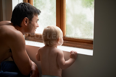 Buy stock photo Rain, window and father with baby in a house for bonding, playing or having fun in their home together. Water, glass or dad with curious kid watching storm, weather or raindrops for learning or games