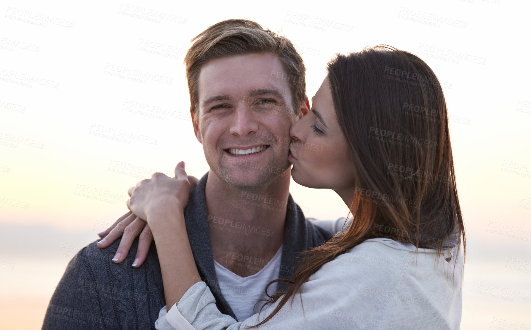 Buy stock photo Love, kiss and couple on beach at sunset for tropical holiday adventure, relax and bonding together. Commitment, happy man and woman on romantic date with ocean, evening sky and embrace on vacation.