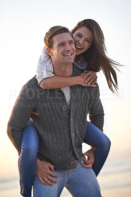Buy stock photo Portrait, piggy back and happy couple on beach at sunset for tropical holiday adventure, relax and bonding together. Love, man and woman on romantic date with ocean, evening sky and travel vacation.
