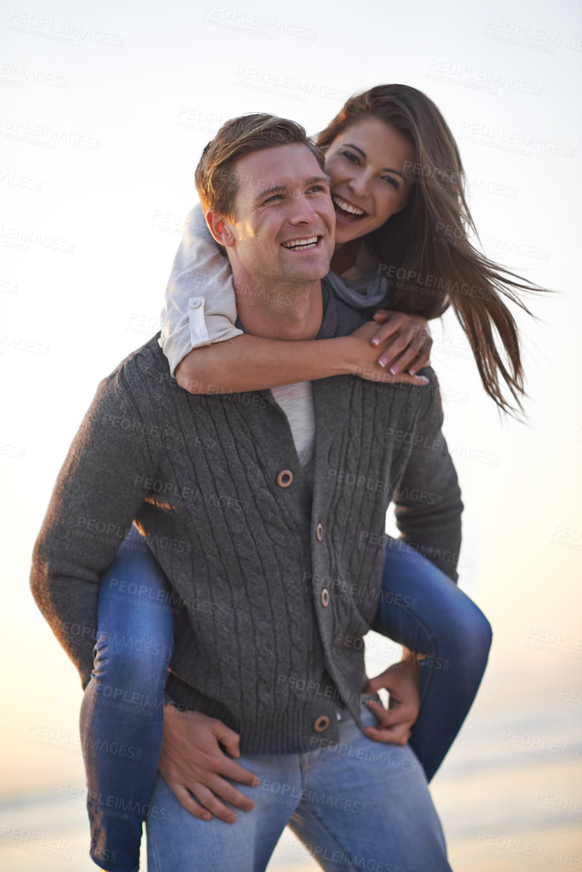 Buy stock photo Portrait, piggy back and happy couple on beach at sunset for tropical holiday adventure, relax and bonding together. Love, man and woman on romantic date with ocean, evening sky and travel vacation.