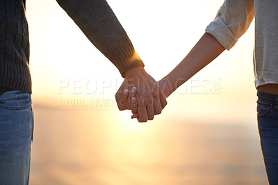 Buy stock photo Cropped whot of a young couple holding hands on the beach