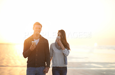 Buy stock photo Couple, coffee and walk at beach on vacation, sunset and holding hands in portrait by ocean. Man, woman and drink with tea cup with smile, bonding and happy for memory on holiday by sea in Australia