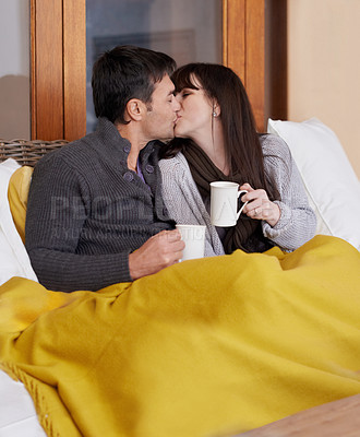 Buy stock photo Love, hug and couple kissing on a sofa with trust, support or bonding with coffee and blanket at home. Mouth, embrace or people in living room with security, safety or romance while chilling with tea