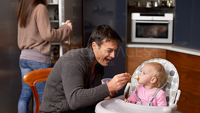 Buy stock photo A young father feeding his baby in the kitchen