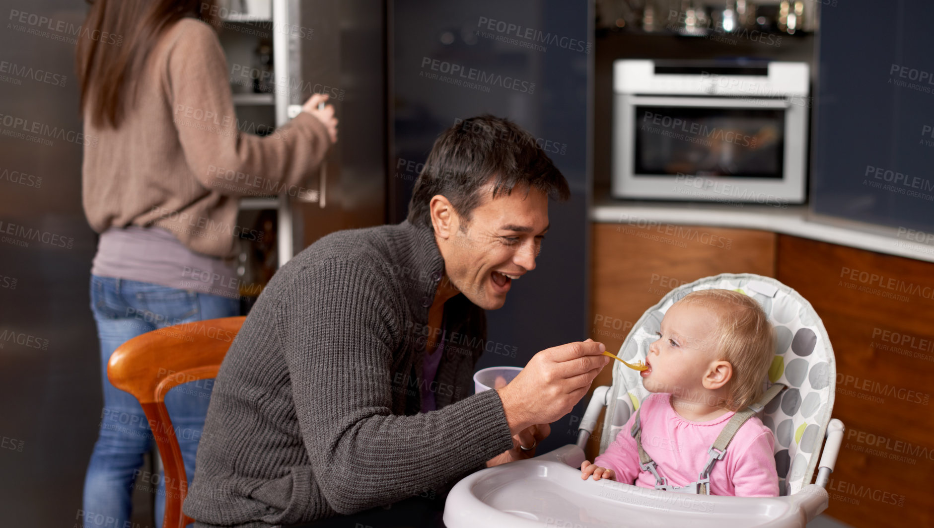 Buy stock photo A young father feeding his baby in the kitchen