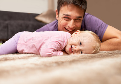Buy stock photo Portrait of a baby lying on the floor with the father in the background