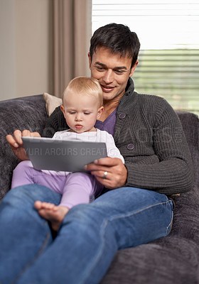 Buy stock photo A young father and his daughter playing on a digital tablet