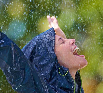 Buy stock photo Cropped shot of a young woman standing happily in the rain in her raincoat