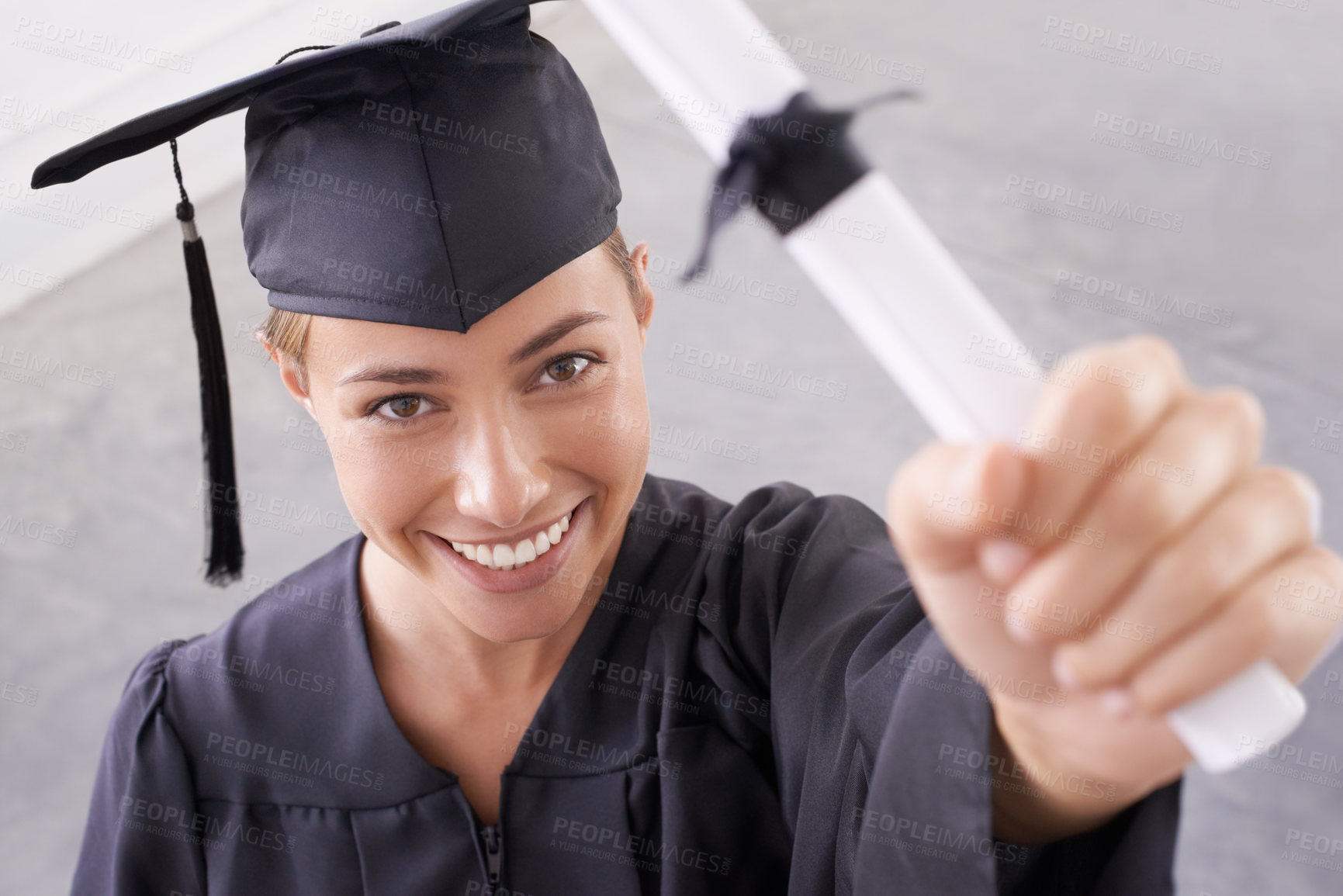 Buy stock photo Portrait of a young female university student holding up her diploma to the camera