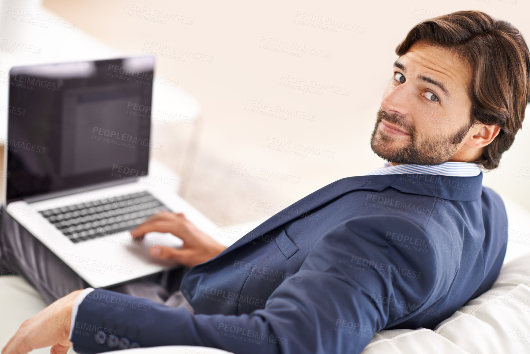 Buy stock photo An attractive businessman sitting on the couch and working on his laptop