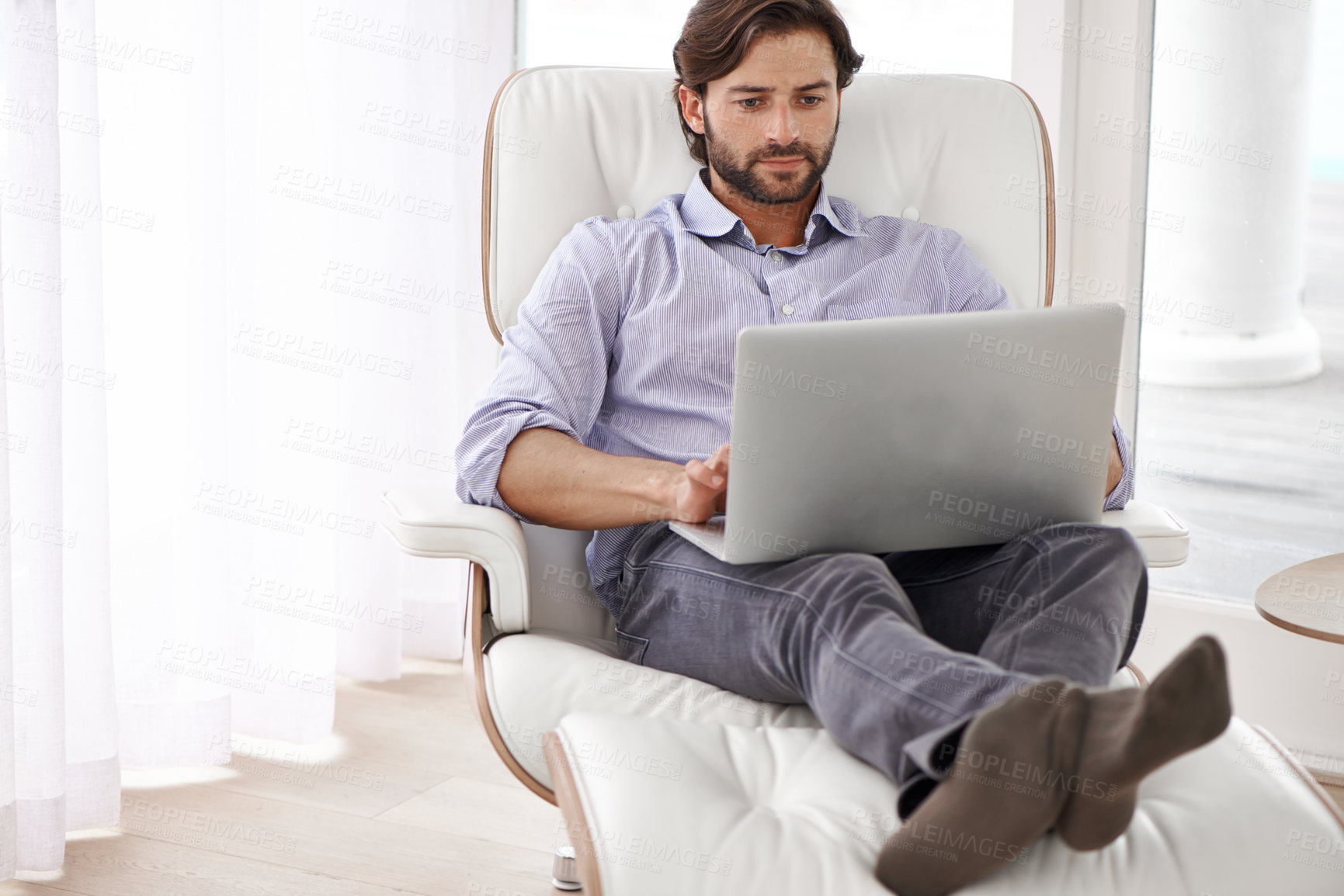 Buy stock photo A handsome businessman  relaxing on his chair while working on his laptop