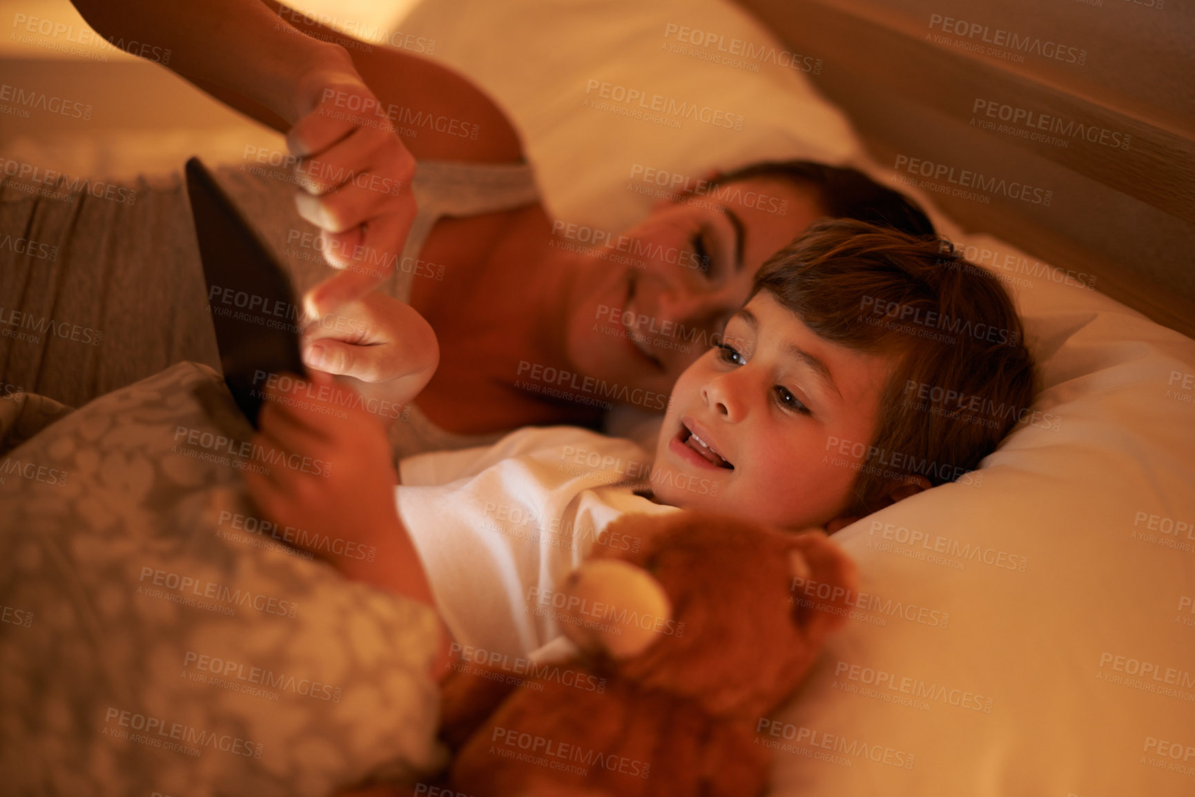Buy stock photo A mother reading a bedtime story to her son from a digital tablet
