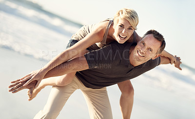 Buy stock photo A husband giving his wife a piggyback ride on the beach