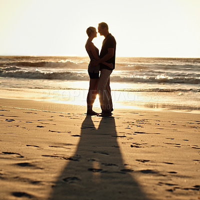 Buy stock photo Silhouette, couple and kiss on beach at sunset for romantic, date and weekend getaway in Turkey. Woman, man or people in love with hug for walk, bonding or together in caring happy relationship