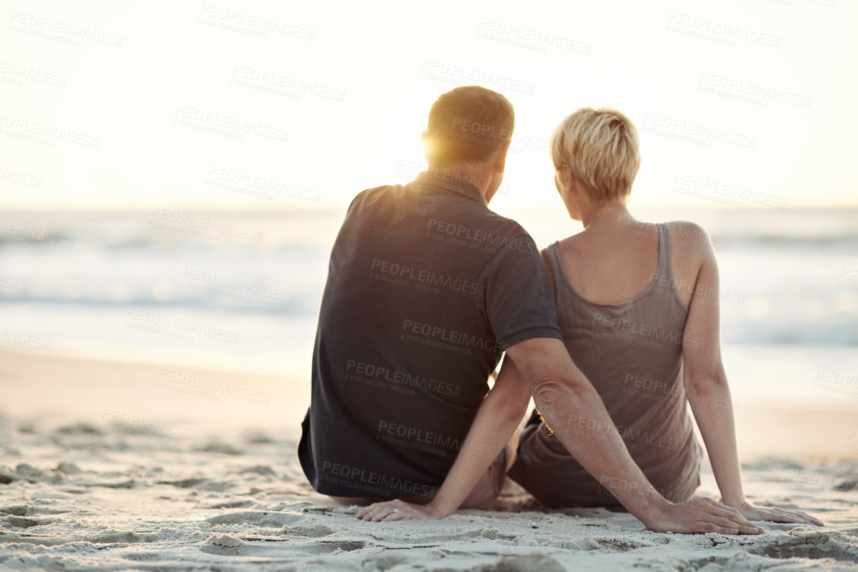 Buy stock photo Nature, beach and back of couple at sunset for bonding, relax together and relationship by ocean. Dating, travel and man and woman hug, embrace and sitting on holiday, vacation and weekend for love