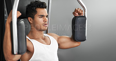 Buy stock photo A fitness shot of an athletic young man using an exercise machine