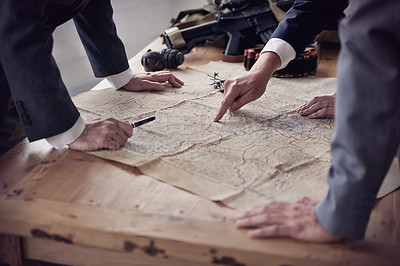 Buy stock photo Two men in suits discussing plans while guns and a map lie on a table