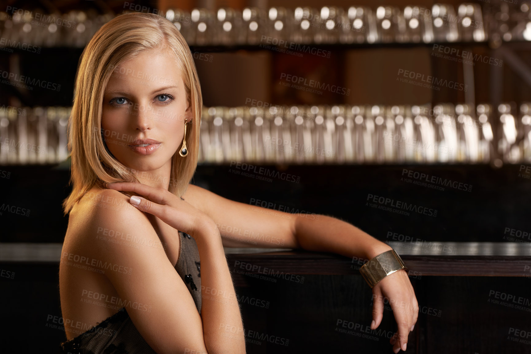 Buy stock photo An attractive and classy young woman standing at the bar of a upper class establishment
