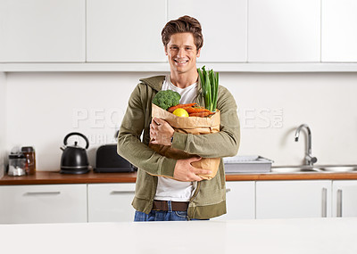 Buy stock photo Portrait, vegetables and man with brown paper bag, home and wellness with nutrition and vegetarian. Face, person and guy with groceries and healthy ingredients with products, food and diet in kitchen