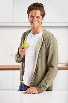 Buy stock photo Smile, portrait and man with apple in kitchen of home for diet, health and wellness. Happy, confident and young male person eating fruit for organic, fresh and nutrition snack in modern apartment.