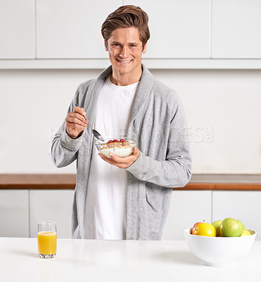 Buy stock photo A handsome young man eating a bowl of granola for breakfast