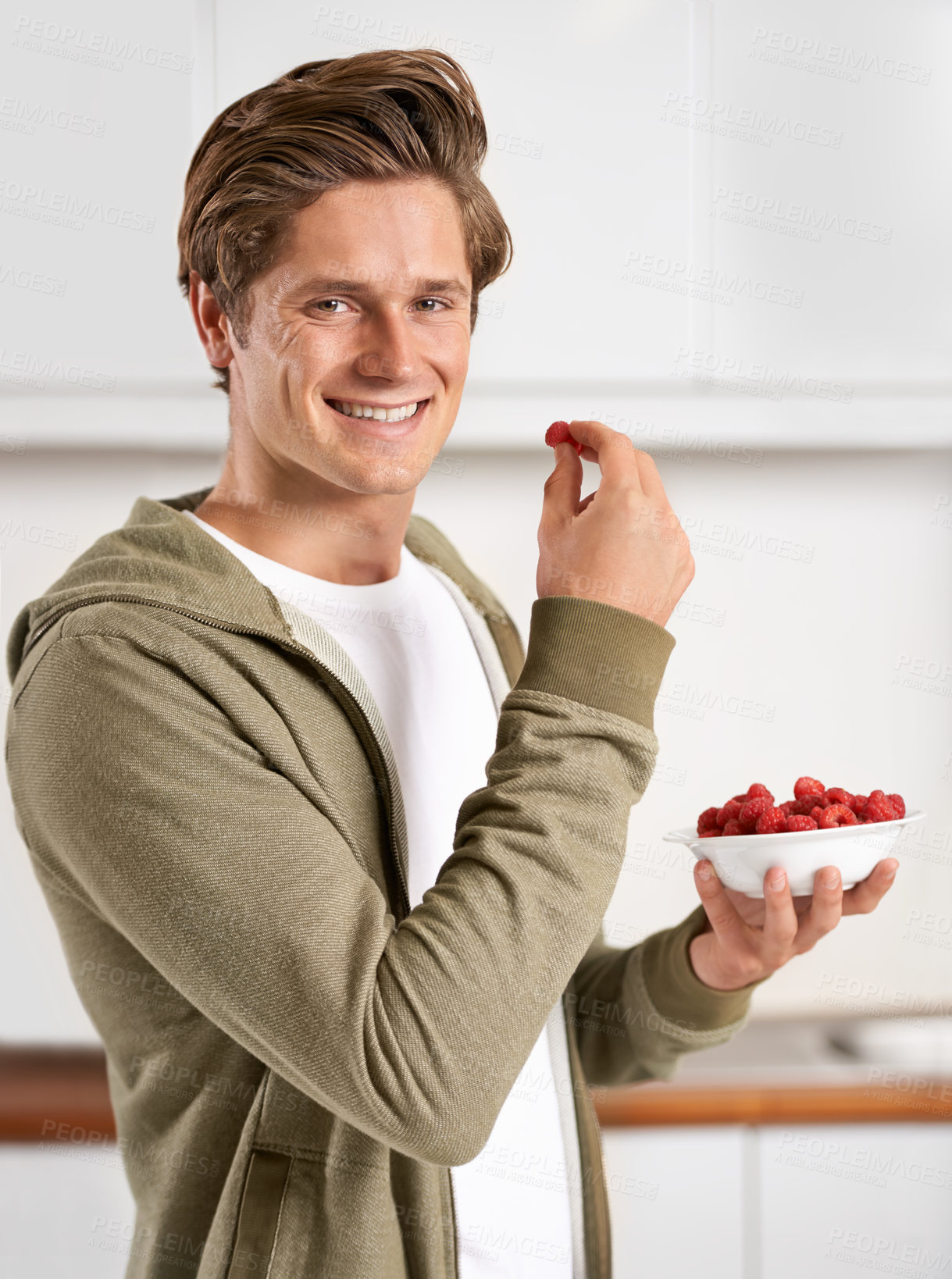 Buy stock photo Smile, portrait and man with raspberries in kitchen of home for diet, health and wellness. Happy, confident and male person eating fruit for fresh, organic or nutrition snack in modern apartment.