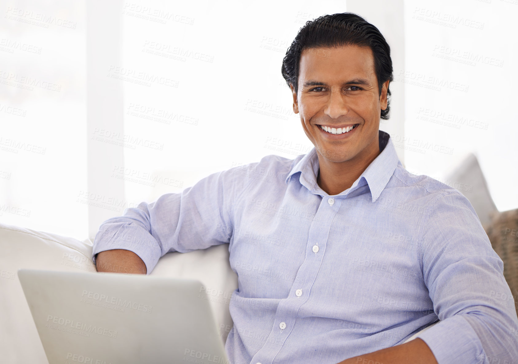 Buy stock photo A handsome young man using his laptop at home