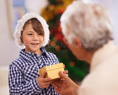 Buy stock photo Grandmother, happy kid and giving Christmas gift in home, love and care at party. Xmas, grandma and child with present at festive celebration, holiday and smile of family bonding together in house