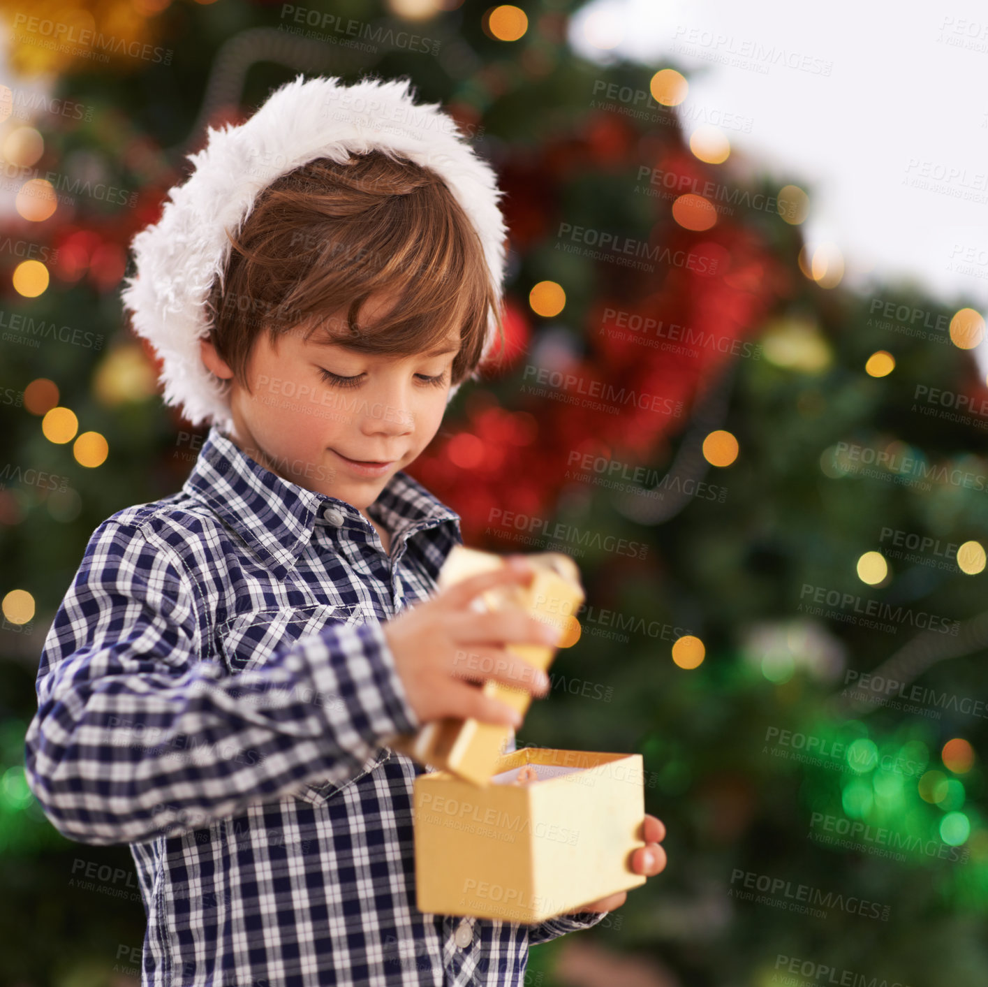 Buy stock photo Happy, Christmas and boy child with gift for celebration or surprise at festive party at home. Smile, santa hat and cute young kid opening a present box for xmas event at modern house with decoration