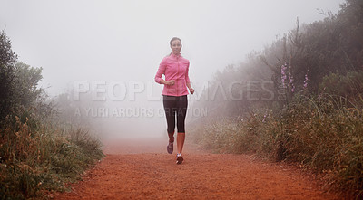 Buy stock photo Shot of a woman running on a trail on a misty morning