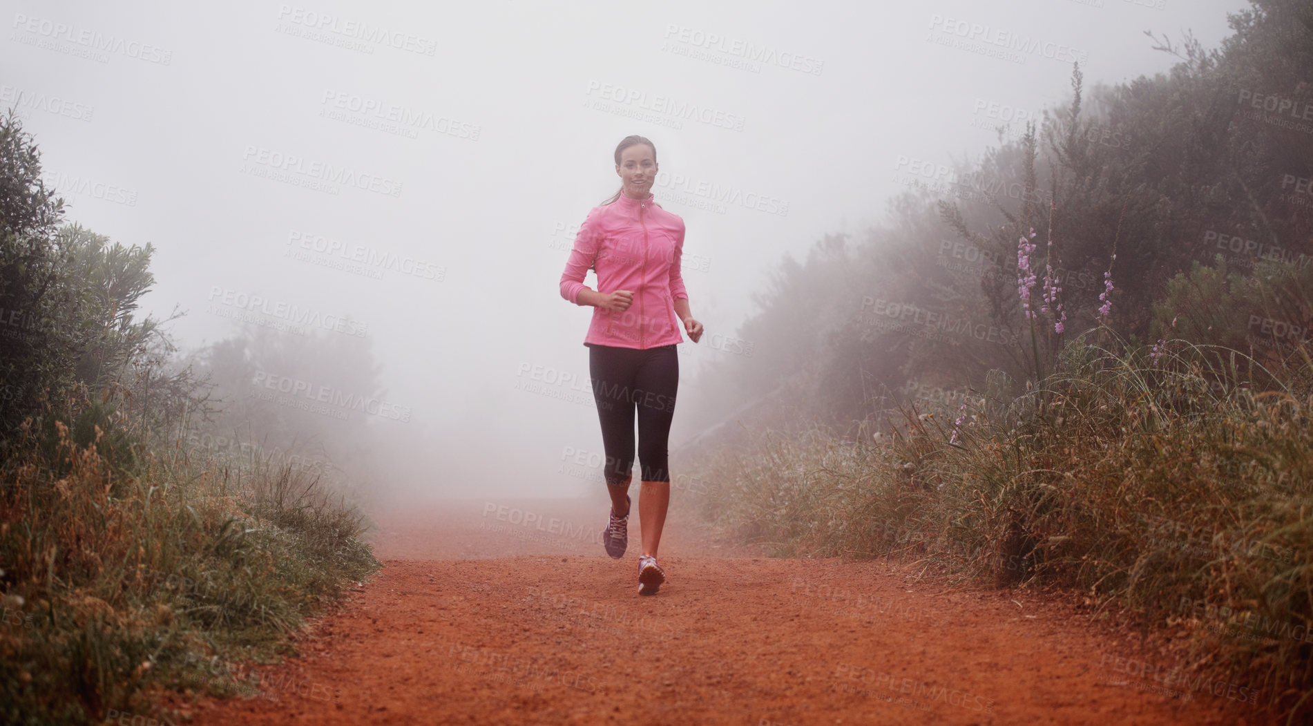 Buy stock photo Shot of a woman running on a trail on a misty morning