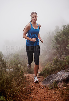 Buy stock photo Woman, face and running in forest with fog for exercise, morning routine and workout with fitness and smile. Athlete, runner and person with happiness on mountain trail for wellness and healthy body