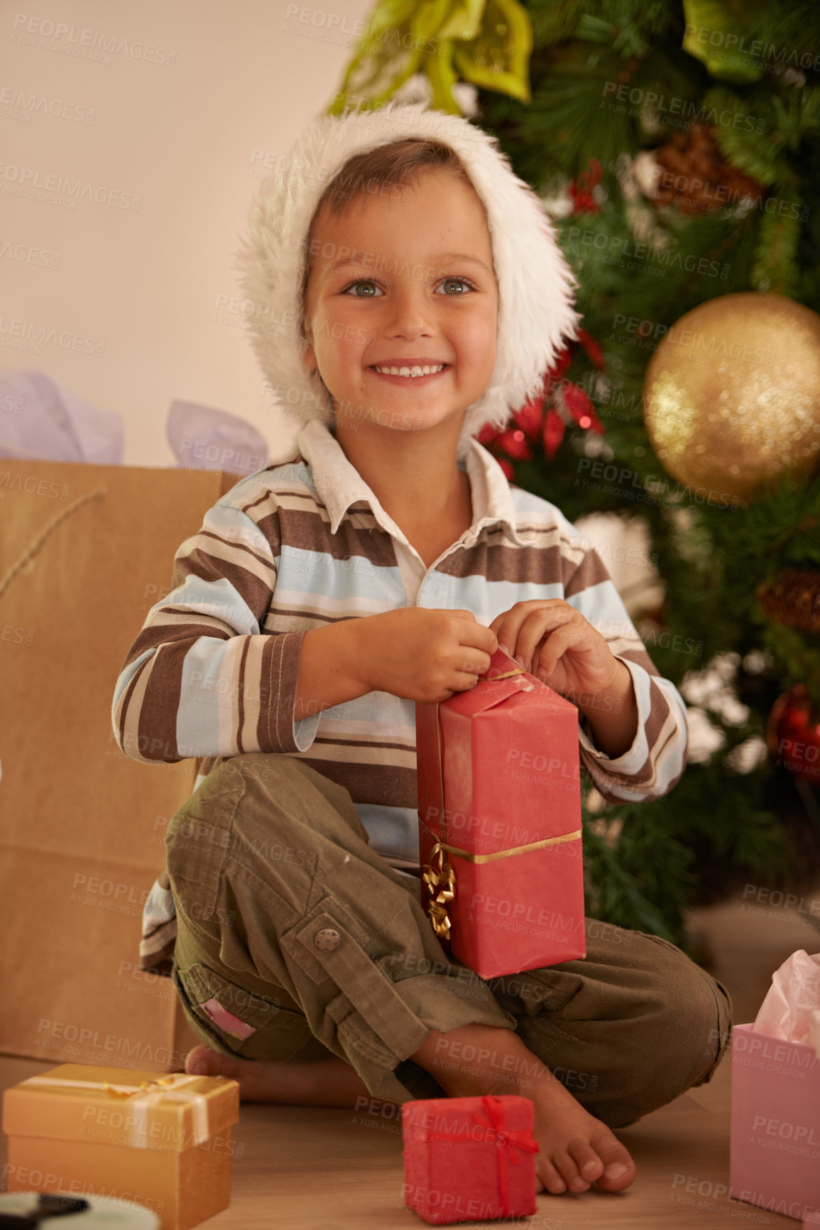 Buy stock photo Shot of a young boy opening a gift on Christmas
