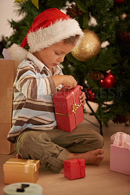 Buy stock photo Boy, child and Christmas present on floor by tree with santa hat for celebration in family home. Kid, xmas and sitting with box, gift or package for festive holiday in house for event in Sweden