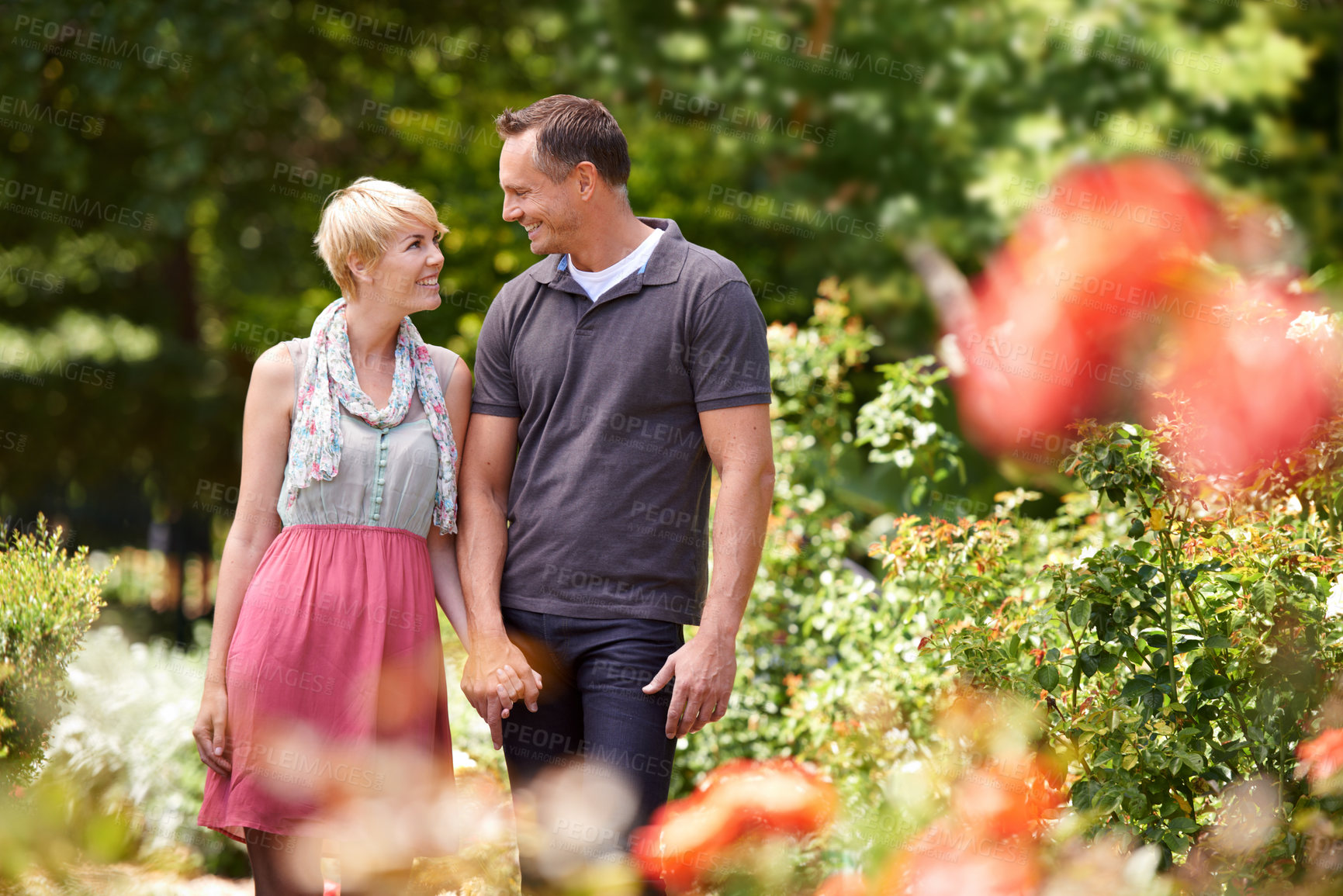 Buy stock photo Love, holding hands and couple in a park with care, support and trust while bonding outdoor. Security, travel and people walking in a field of flowers for holiday, vacation or romantic summer date