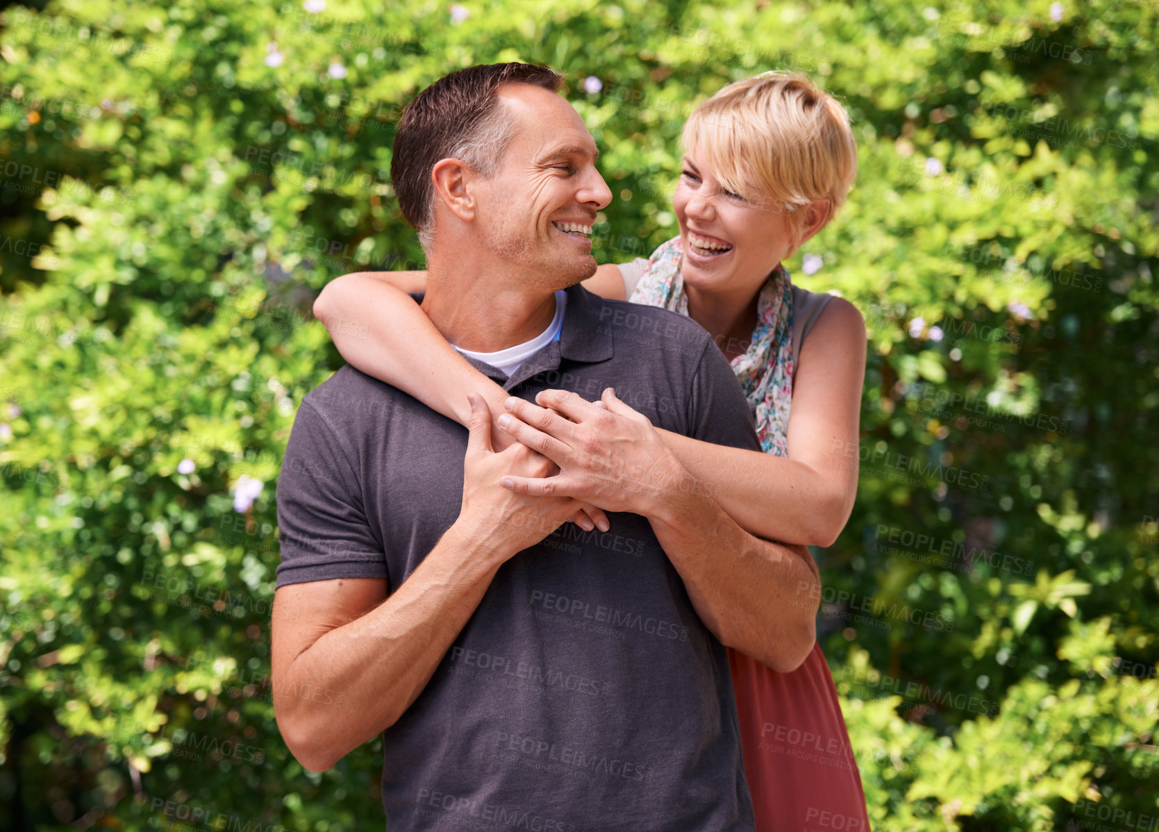 Buy stock photo Love, hug and couple laughing in a park for travel, adventure and bonding in nature together. Smile, romance and people embrace in forest for summer date, reunion or weekend, holiday or support fun