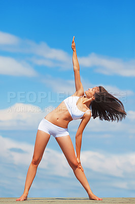 Buy stock photo A young woman doing yoga on a roof against a blue sky