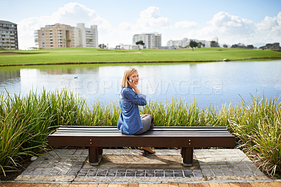 Buy stock photo Rear view shot of a blonde woman talking on her phone on the park bench