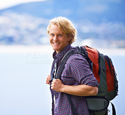 Buy stock photo Man, trekking and portrait on mountains for travel, adventure and wellness by ocean, sea and vacation in Europe. Face of an excited, young person with backpack for hiking, explore and outdoor journey