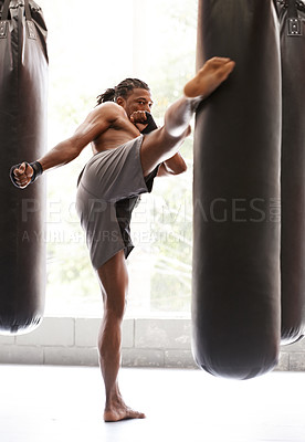 Buy stock photo Man, kick boxing and bag with exercise, foot and combat for training with balance, power and precision in gym. African athlete, person or fighter with workout, fitness or strike for challenge in dojo