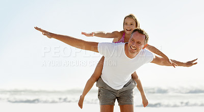 Buy stock photo Shot of a young girl on her father's back at the beach