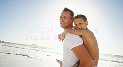 Buy stock photo Shot of a young boy on his father's back at the beach
